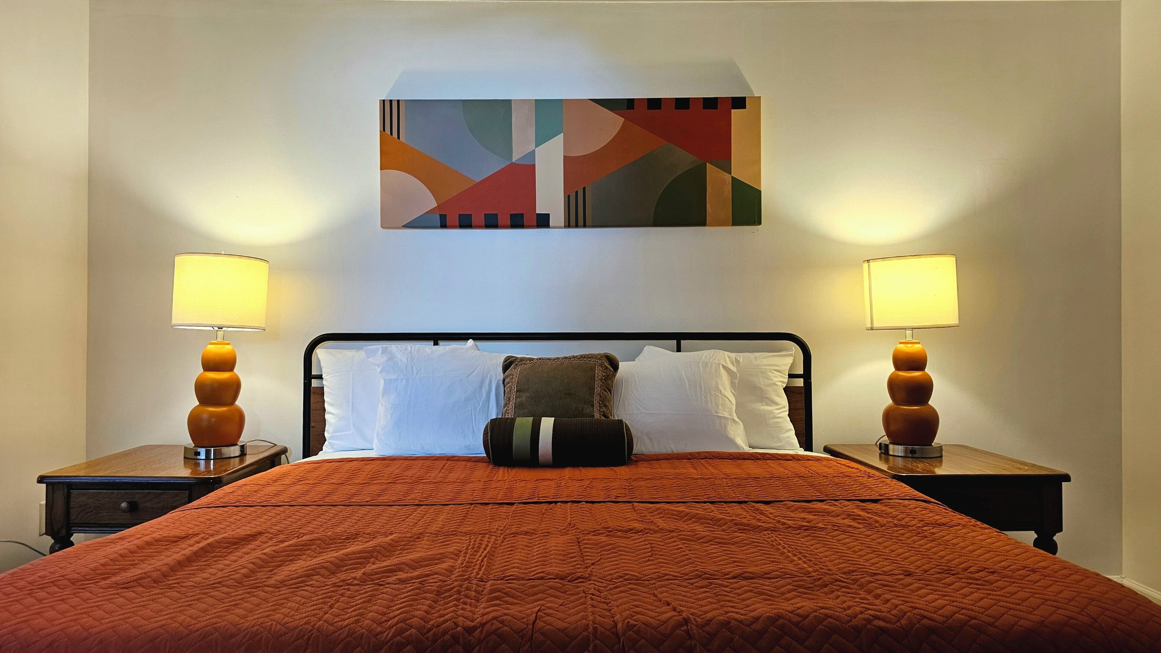 Une chambre d’hôtel avec un lit, deux lampes de chevet, une œuvre d’art murale et une fenêtre.