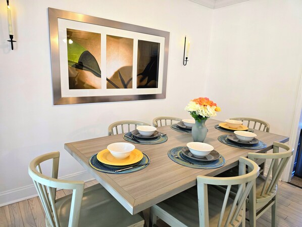 Une table à manger ornée d’un vase de fleurs, de bols et d’assiettes, le tout préparé pour six personnes.