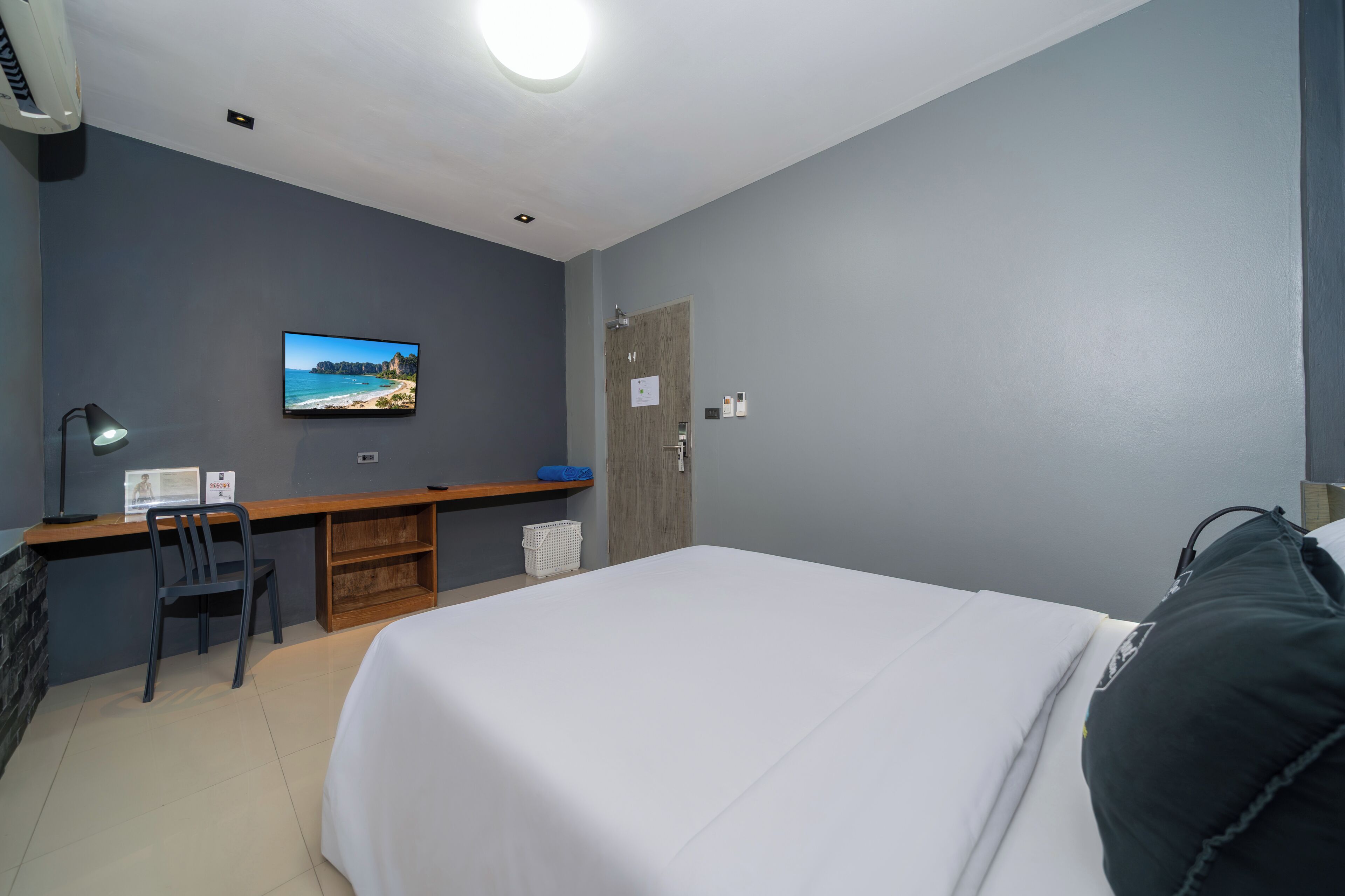 Een hotelkamer met een bed, een bureau met stoel, een televisie en een deur.