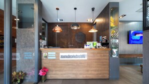 A reception desk with a wooden finish, a digital display, and a sign in a foreign language. - Dent Station Residence (Chalong)