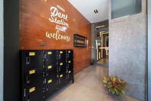 A dental office entrance with a welcome sign, a row of black lockers, and a potted plant.