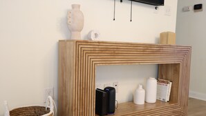 A wooden console table with a geometric pattern, a black speaker, and a white vase. - Cozy Stylish 2 BR Home w / Relax & Enjoy (Owensboro)