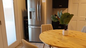 A kitchen with a stainless steel refrigerator, a water dispenser, a round wooden table, and chairs. - Cozy Stylish 2 BR Home w / Relax & Enjoy (Owensboro)