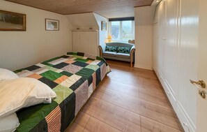 A bedroom with a bed, a window, a sofa, and a wardrobe.
