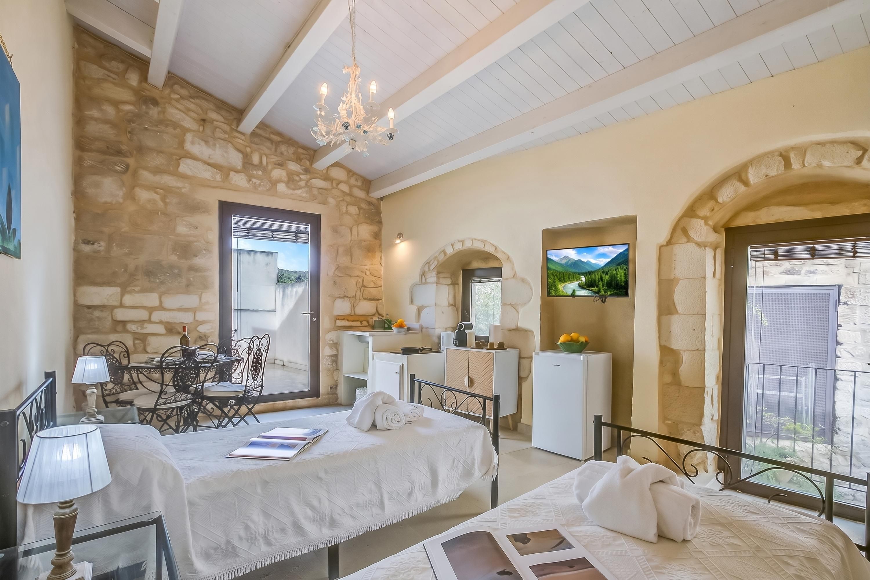 A bedroom with a stone wall, a bed, a desk, a chair, a TV, and a balcony.