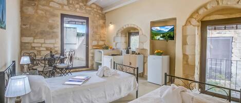 A bedroom with a stone wall, a bed, a desk, a chair, a TV, and a balcony.