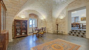 Um quarto com paredes de pedra, uma mesa de jantar, cadeiras, um tapete e um armário de madeira.