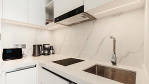 A modern kitchen with white marble countertops, stainless steel appliances, and a sleek faucet. - Unit 2303 Beachfront | Pool-Facing + Sea View (Choeng Thale)
