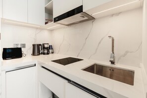 A modern kitchen with white marble countertops, stainless steel appliances, and a sleek faucet. - Unit 2303 Beachfront | Pool-Facing + Sea View (Choeng Thale)
