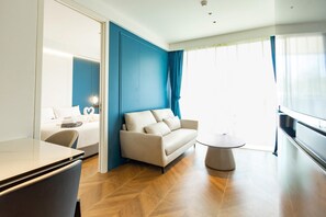 Ein modernes Hotelzimmer mit einer Couch, einem kleinen runden Tisch und einem Bett mit einem Nachttisch.