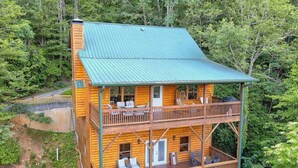 Een houten chalet met meerdere verdiepingen en balkons, omringd door een dicht bos.