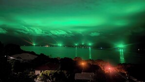 A nighttime view of a body of water with a green aurora display above and a bridge in the distance. - Room-pillais B & B, Private Room Attach (Albany)