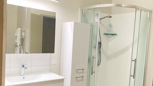 A modern bathroom with a glass-enclosed shower, a white vanity with a mirror, and a light-colored floor. - Fabulous residence in New Plymouth (New Plymouth)