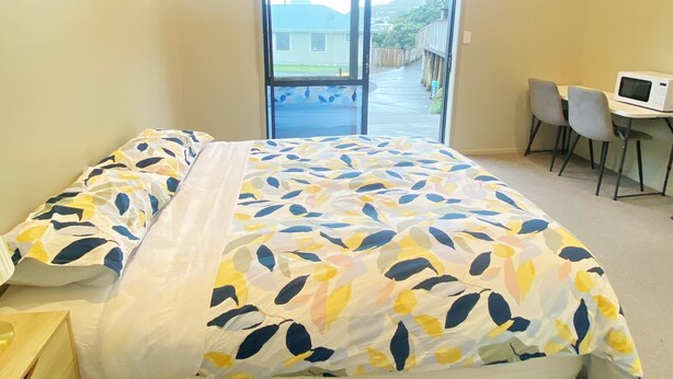 A bedroom with a bed, a desk with a chair, a window, and a view of the outside. - Fabulous residence in New Plymouth (New Plymouth)