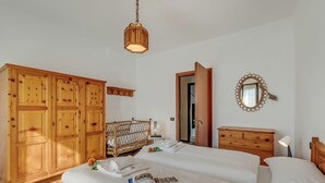 Ett hotellrum med en stor garderob, en säng med vita sängkläder, ett nattduksbord med en lampa och en spegel på väggen.