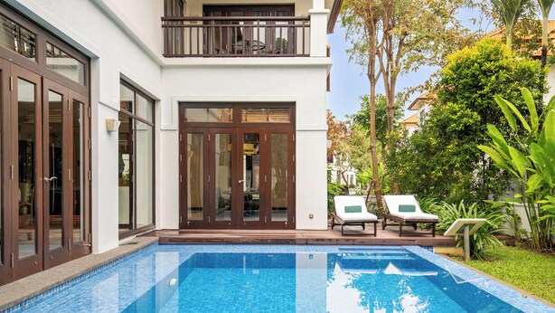 Ein modernes Haus mit Swimmingpool, zwei Liegestühlen und einem Balkon.