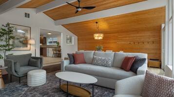 Un vaste espace de vie doté d’un haut plafond, d’un ventilateur de plafond, d’un luminaire, d’un canapé, d’une table basse et d’une table d’appoint.