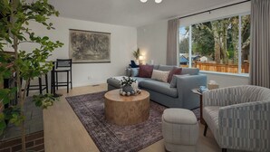 Ein modernes Wohnzimmer mit einer Couch, Sesseln, einem Couchtisch und einem großen Fenster mit Blick.
