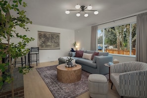 A modern living room with a sofa, armchairs, a coffee table, and a large window with a view.