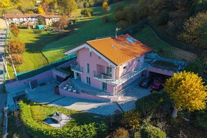 Ein mehrstöckiges Haus mit einem geneigten Dach, einem Balkon und einem kleinen Garten.