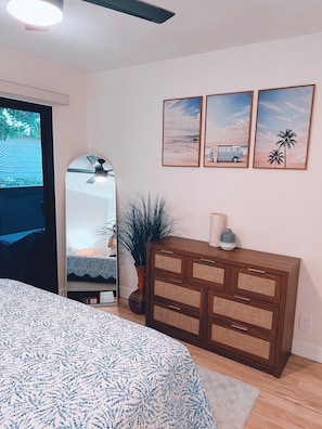 A bedroom with a bed, dresser, mirror, and wall art.