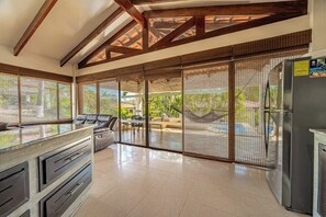 A spacious kitchen with a large island, sliding glass doors to a patio, and a modern refrigerator. - Exquisite villa with fully-equipped kitchen, plunge pool & beach shuttle (Playa Hermosa)