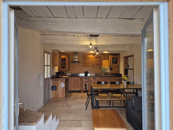 A kitchen with wooden cabinets, a dining table, and a bench.