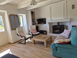 Un salon avec une cheminée, deux fauteuils, un canapé et un téléviseur.