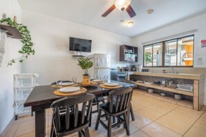 Eine kompakte Küche mit Esstisch, Stühlen, Deckenventilator, Fernseher und einem Fenster mit Aussicht.