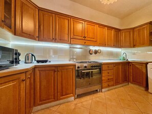 A kitchen with wooden cabinets, a stove, and a sink. - "Family Vacation Apartment" (Bari Sardo)