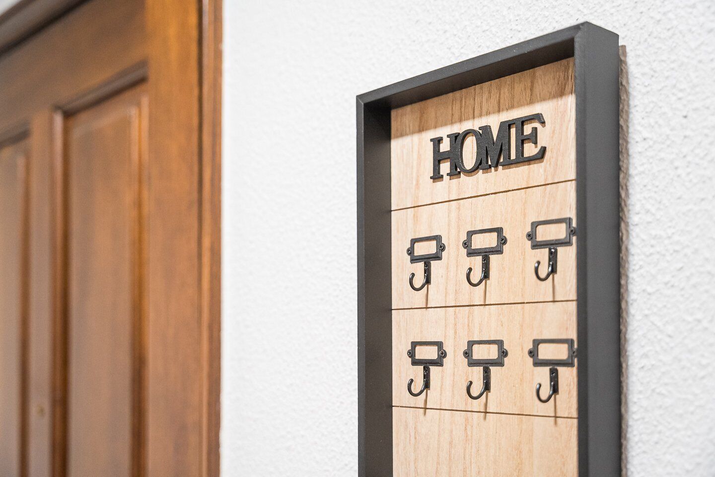 A wooden sign with 'HOME' and multiple hooks, likely for keys, mounted on a wall.