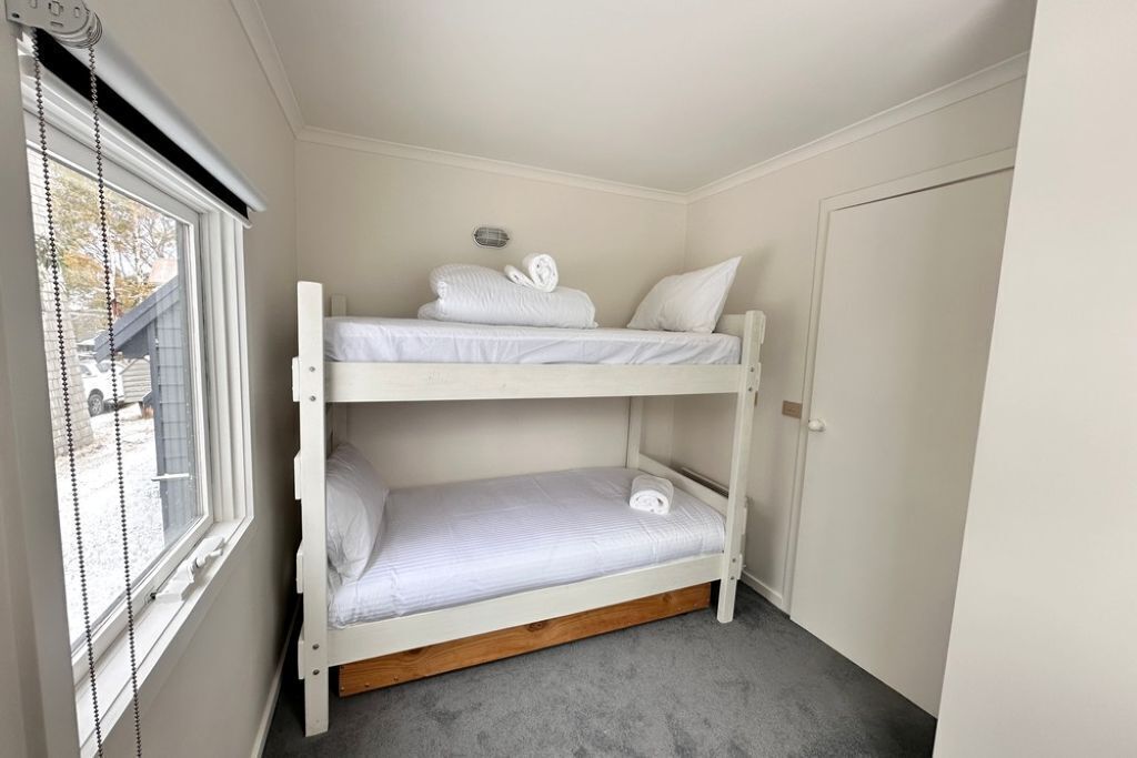 A bunk bed room with a window, a door, and a ceiling light.
