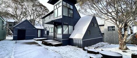 A modern two-story house with a large garage, a covered porch, and a snow-covered yard.