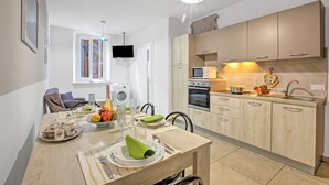 A modern kitchen with wooden cabinets, a built-in oven, and a microwave. - Casa Paolo - Sea Front with Balcony, Ceriale, Italy (Ceriale)
