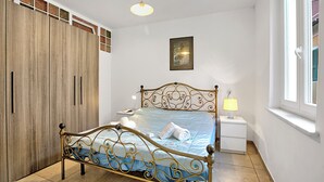 A bedroom with a bed, wardrobe, bedside table, lamp, and a window. - Casa Paolo - Sea Front with Balcony, Ceriale, Italy (Ceriale)