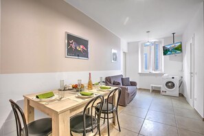 A modern living space with a dining area, a sofa, a TV, and a washing machine. - Casa Paolo - Sea Front with Balcony, Ceriale, Italy (Ceriale)