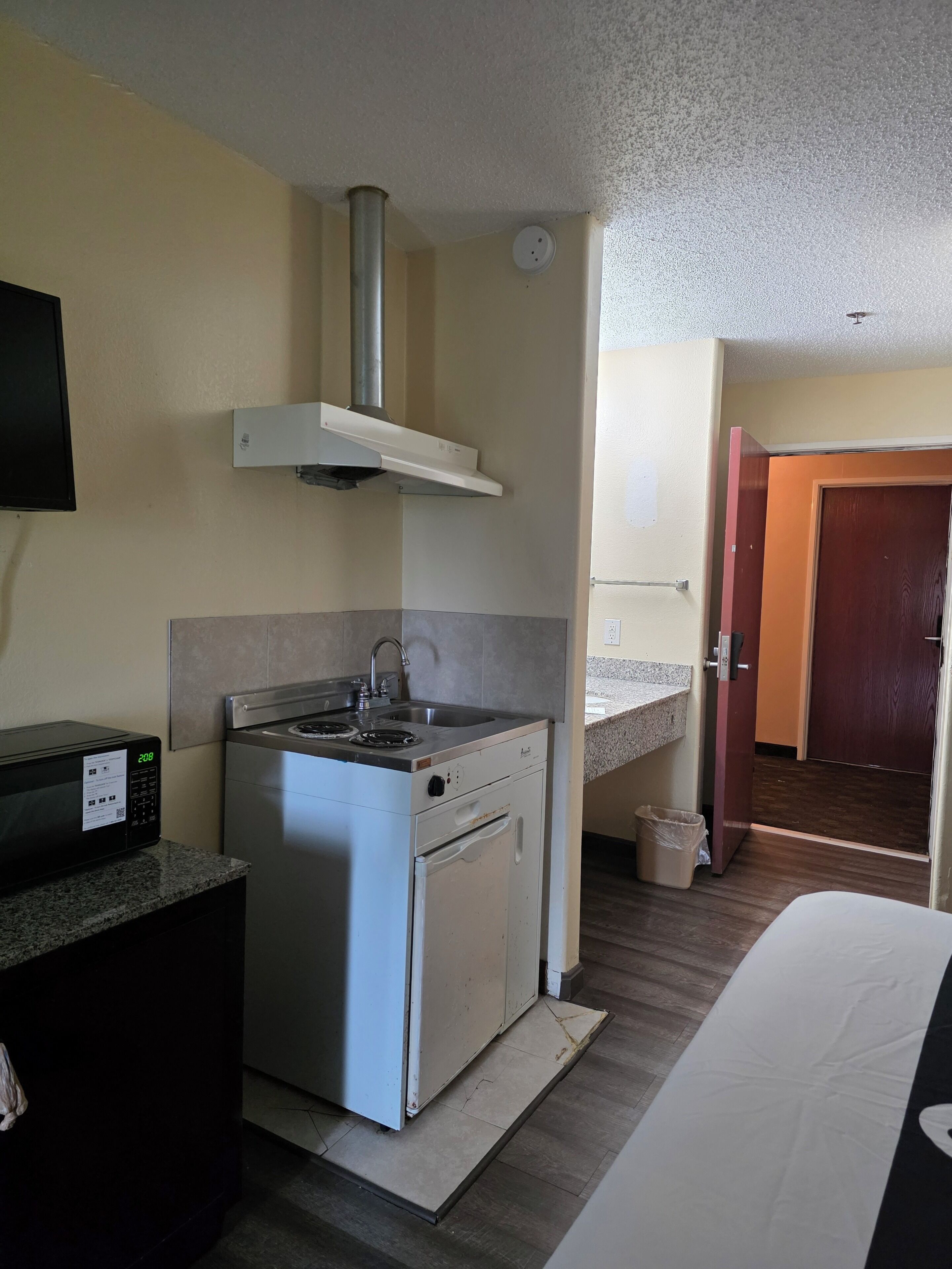 A compact kitchenette with a stove, sink, and a microwave.