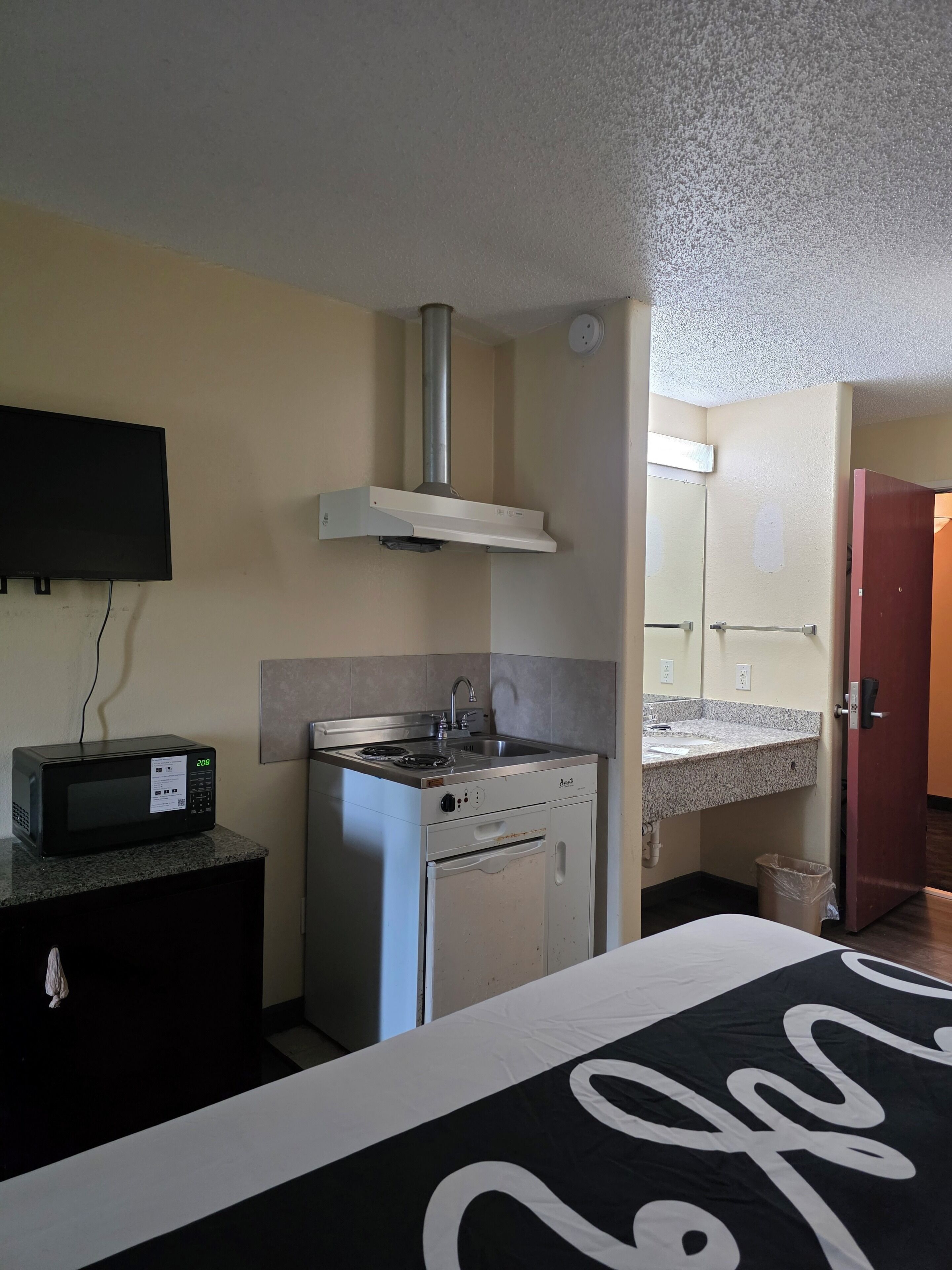 A compact kitchenette with a microwave, stove, and sink.