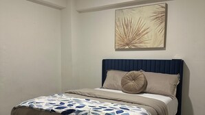 Ein Schlafzimmer mit Bett, Kopfteil, Wandbild und Deckenleuchte.