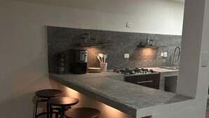 Eine moderne Küche mit Barbereich, inklusive Barhocker, einer Kaffeemaschine und einem Gasherd.