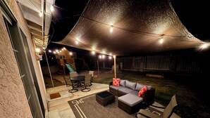 An outdoor patio area with a covered seating area, a table, and a slide. - Centrally Located, Family friendly Home- With Game Room and Infrared Sauna (Farmington)