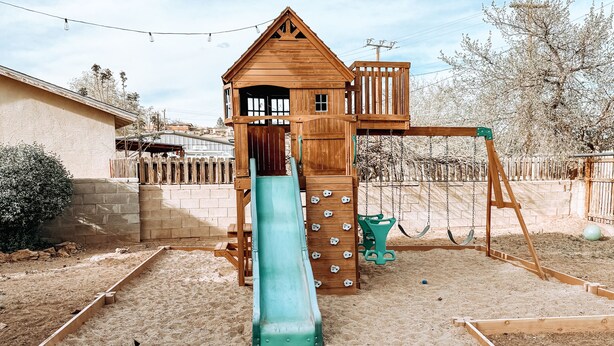 A wooden playhouse with a slide, swings, and a sandbox. - Centrally Located, Family friendly Home- With Game Room and Infrared Sauna (Farmington)