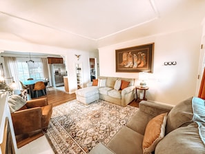 A living room with a sofa, armchairs, a rug, and a dining area with a table and chairs. - Centrally Located, Family friendly Home- With Game Room and Infrared Sauna (Farmington)