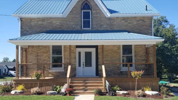 A two-story house with a gabled roof, a front porch, and a small garden. - Small Town Charm (Clifford)