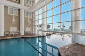 A swimming pool with clear blue water, large windows, and a view of the beach. - Majestic Sun — Gulf Views, Heated Pool + Hot Tubs (Miramar Beach)