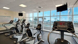 Een fitnessruimte met loopbanden, een crosstrainer en een hometrainer.