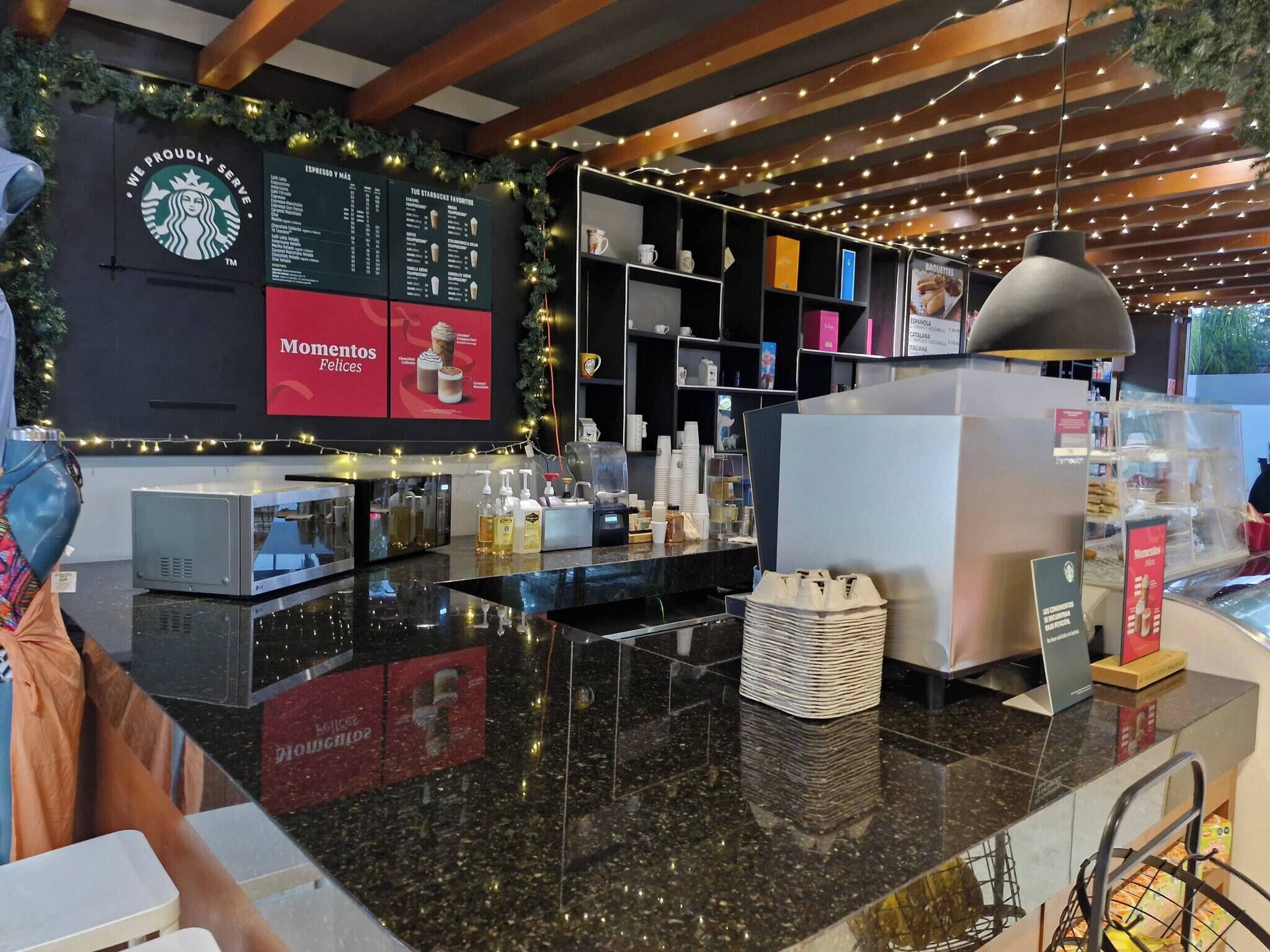 Een Starbucks koffie winkel interieur met een balie, menuborden en een display met gebak.