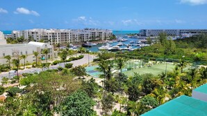 A marina with boats, a tennis court, and a hotel with multiple buildings. - Beautiful PH in Front of the Marina (Punta Sam)