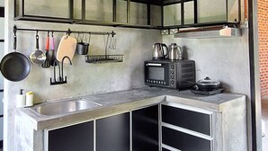 Una cocina con microondas, hervidor y estufa integrados.