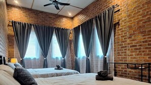 Un dormitorio con pared de ladrillo, dos camas, ventilador de techo y cortinas.